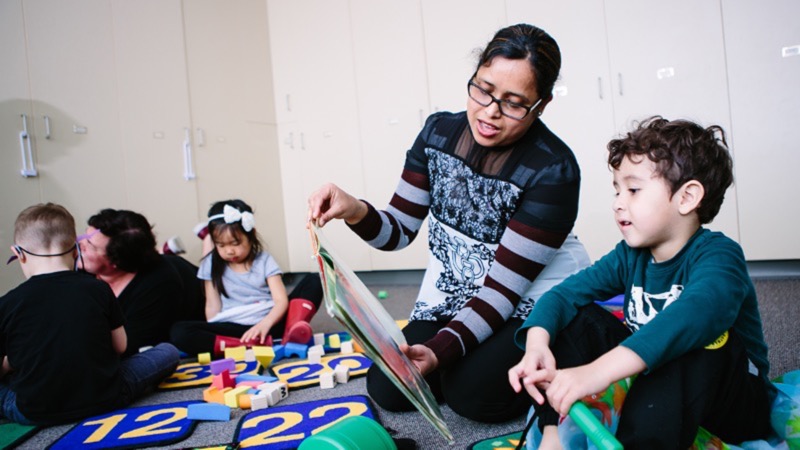 An educator reading a book to a child