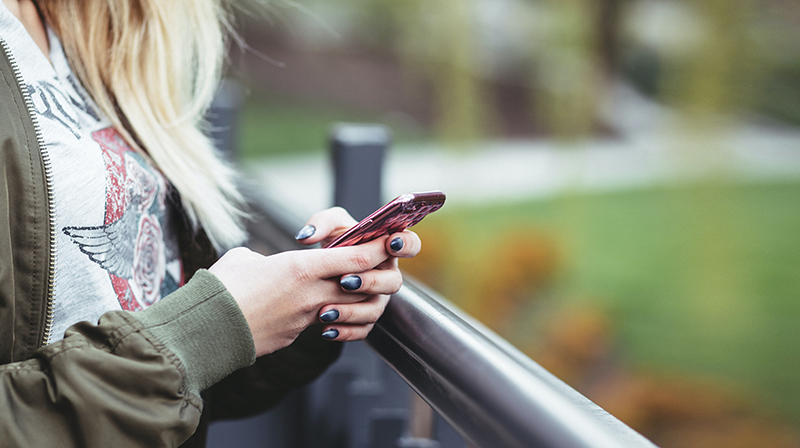 A woman holding an iPhone outdoors