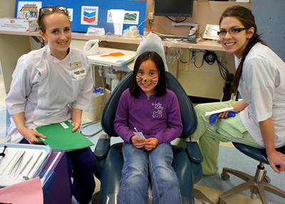 VCC dental students cleaning a little girl's teeth.